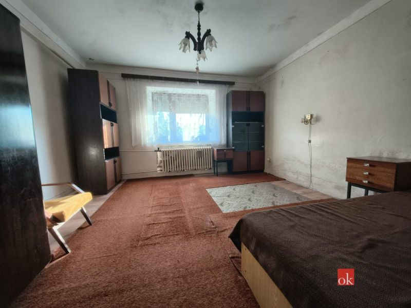 A bedroom in a family house with carpet and older furniture.