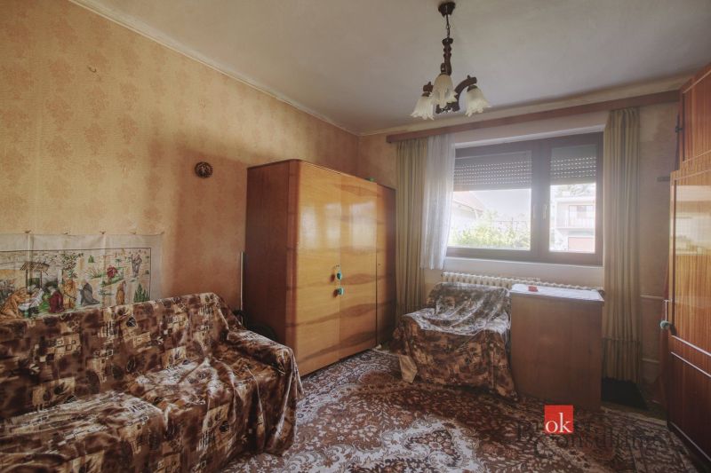A room in a family house with furniture, wallpaper, and carpet.