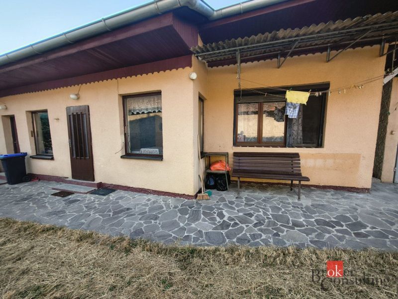 A family house in Ladice with a stone path and a bench by the wall.