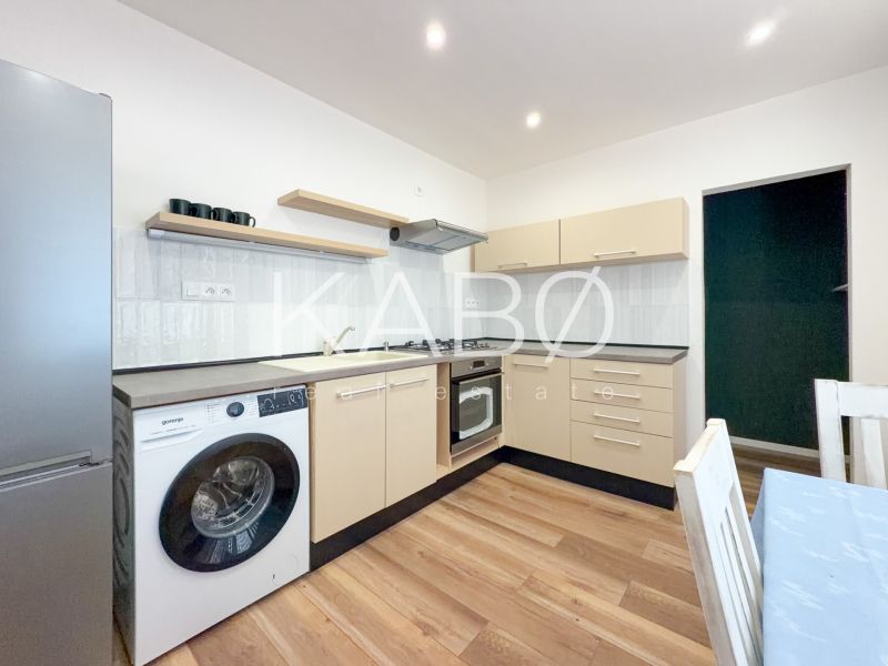A kitchen in a 2-room apartment with a wooden decor floor, light furniture, and appliances.