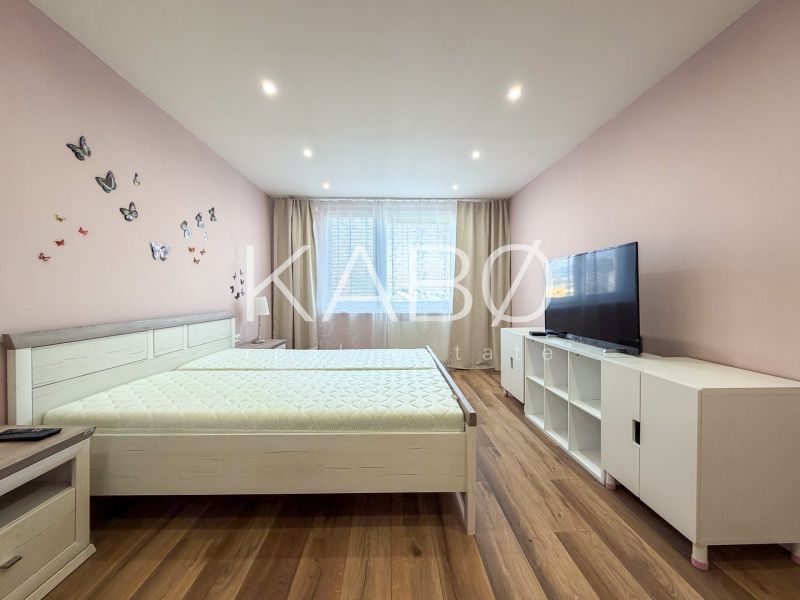 A bright bedroom with butterflies on the wall and a wooden decor floor in a 2-room apartment.