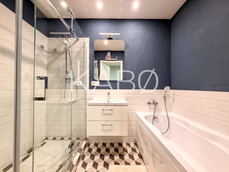 Bathroom in a 2-room apartment with a shower, bathtub, and white tiles.