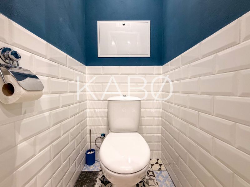 A bathroom in a two-room apartment with white tiles and dark blue walls.