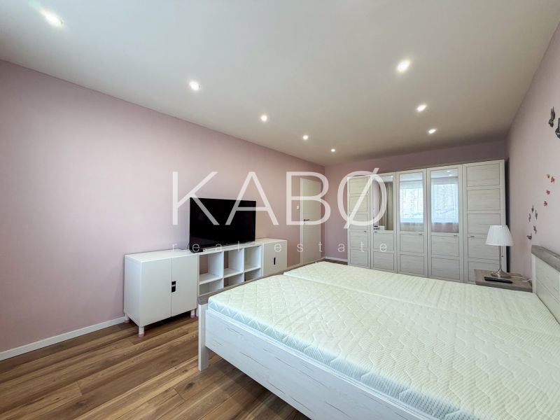 A bedroom in a two-room apartment with a wooden decor floor and white furniture.