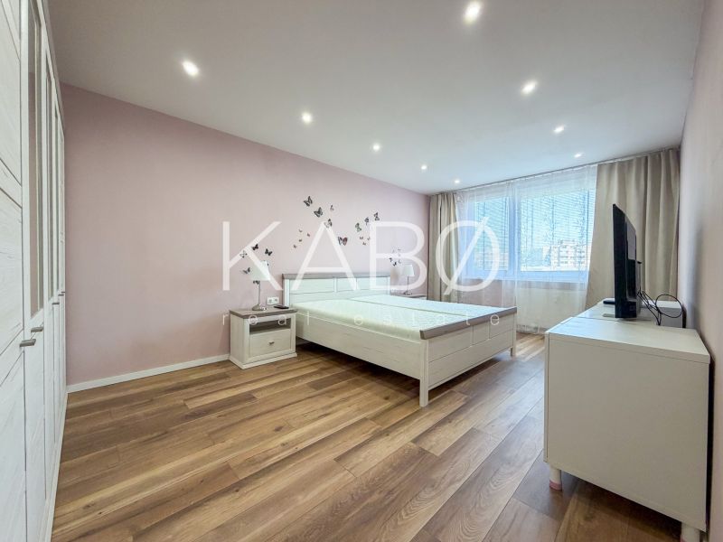 A bright bedroom with wood-patterned flooring in a two-room apartment.