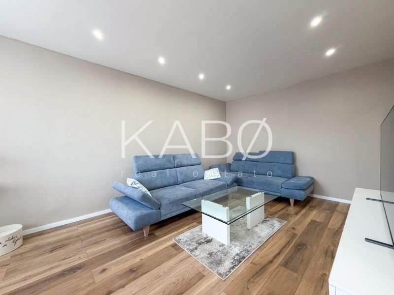 Living room with a blue sofa and a glass table, floor with a wooden decor.