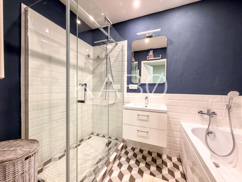 A bathroom in a 2-room apartment with a bathtub, shower, and designer tiles.