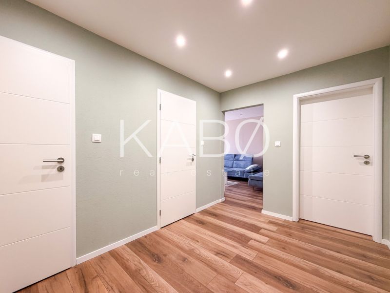 A hallway in a 2-room apartment with a wooden decor floor and white doors.