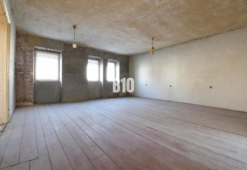 A spacious room with three windows and a wooden decor floor.