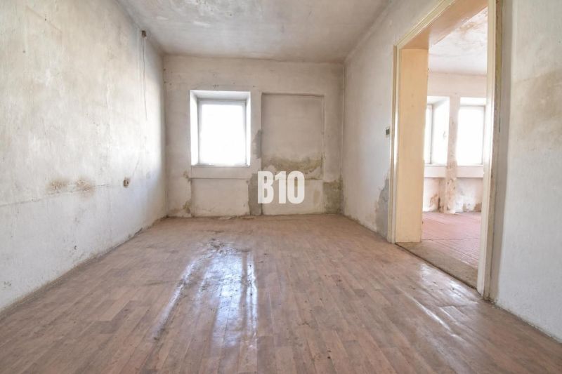 Room in a family house with a wooden decor floor and a damaged wall.