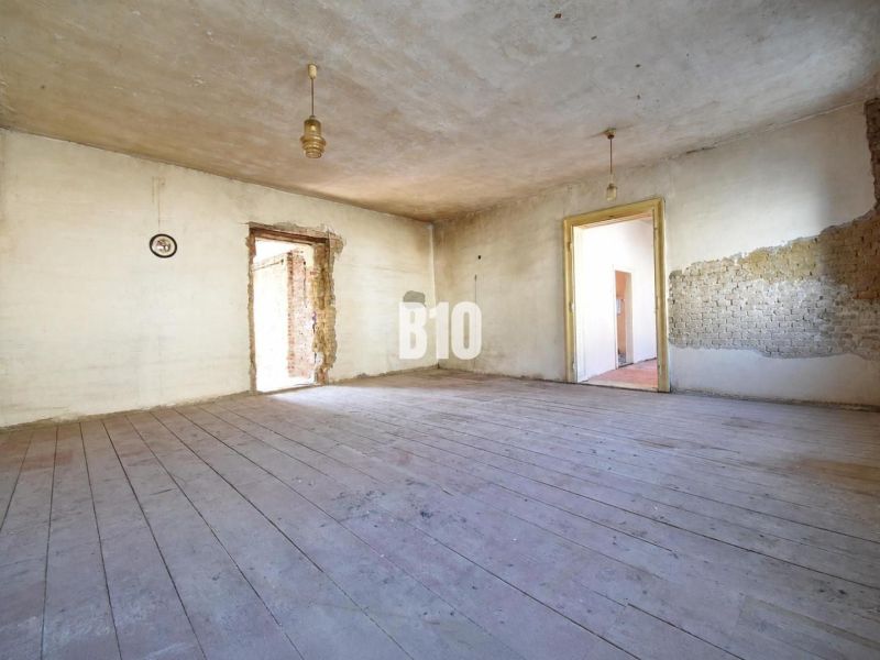 A spacious room with a wooden decor floor in a family house, suitable for renovation.