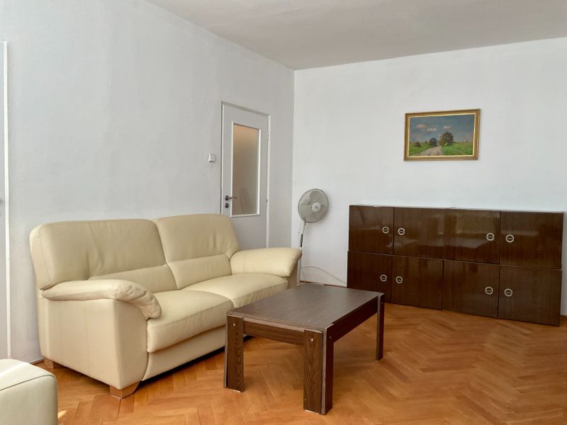 Living room with a cream sofa, wooden table, and a cabinet on the floor with a wooden decor.