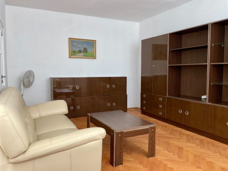Living room in a two-room apartment with a wooden decor floor, sofa, and cabinets.