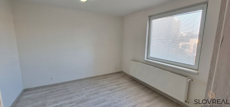 A room in a 2-room apartment with white walls and a wooden decor floor.