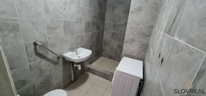 Bathroom with tiles, sink, toilet, and washing machine in a 2-room apartment.