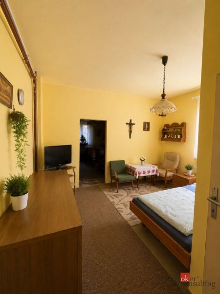 A room in a family house with wooden furniture, a carpet, and yellow walls.