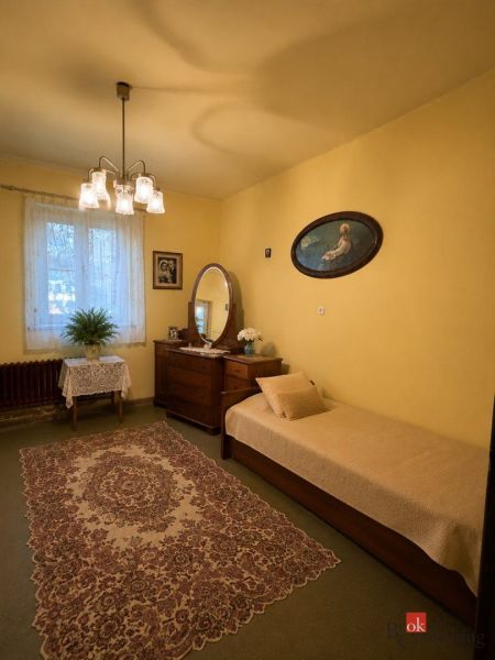 A room in a family house with carpeted flooring, yellow walls, a bed, and a mirror.