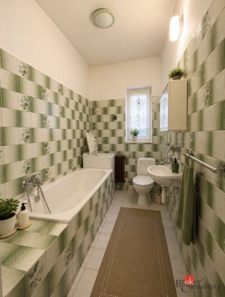Bathroom in a family house with ceramic tiles and a bathtub in green shades.