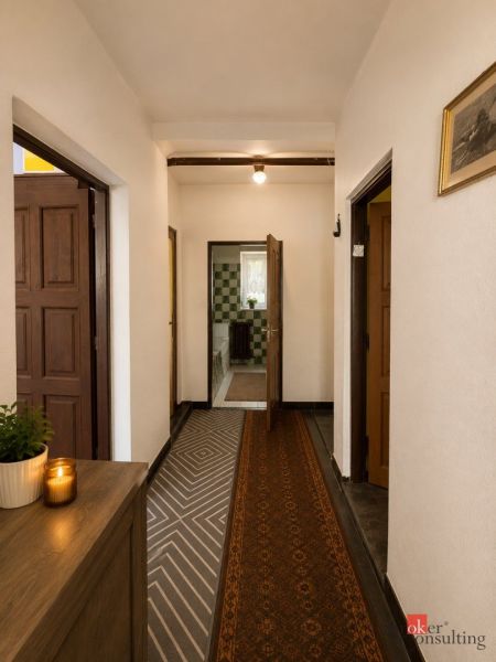 A hallway in a family house with a carpet runner, wooden furniture, and a decorative candle.