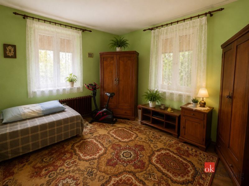 Green walls, carpet, wooden furniture, and an exercise bike in a family house.