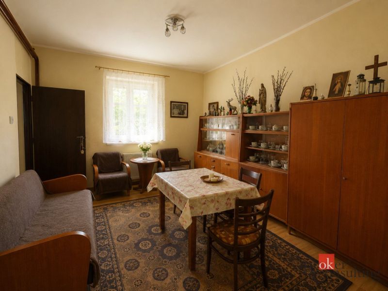 Living room with wooden furniture, wood-patterned flooring, a carpet, and decorative items.