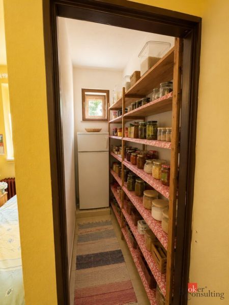 A pantry in a family house with shelves full of preserves and a window.