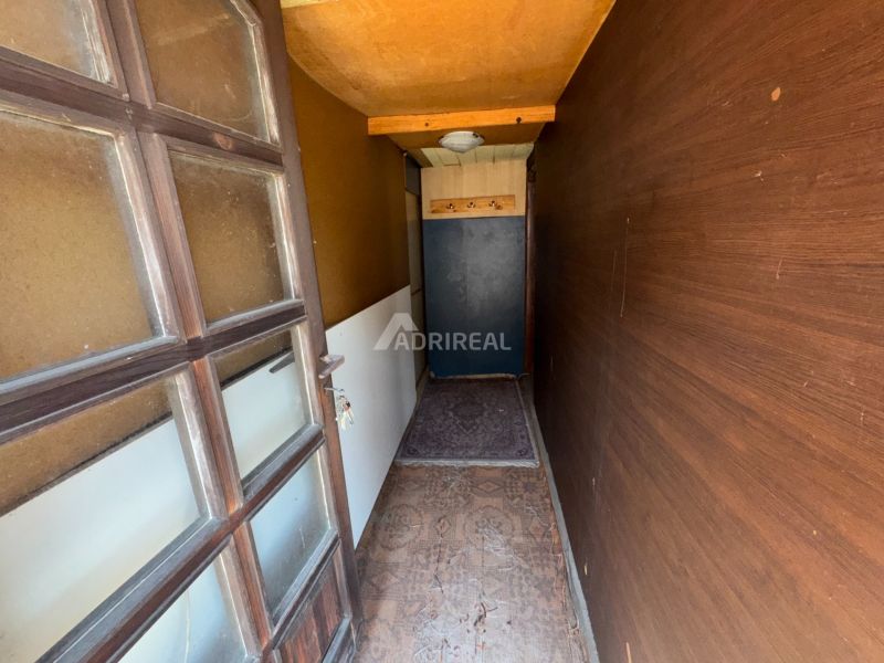 A narrow hallway with a wooden wall and carpet in a family house.