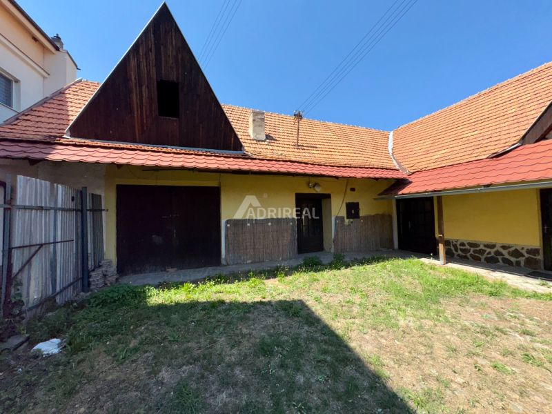 The courtyard of a family house in Dobrá Niva with a grassy area and a sloped roof.