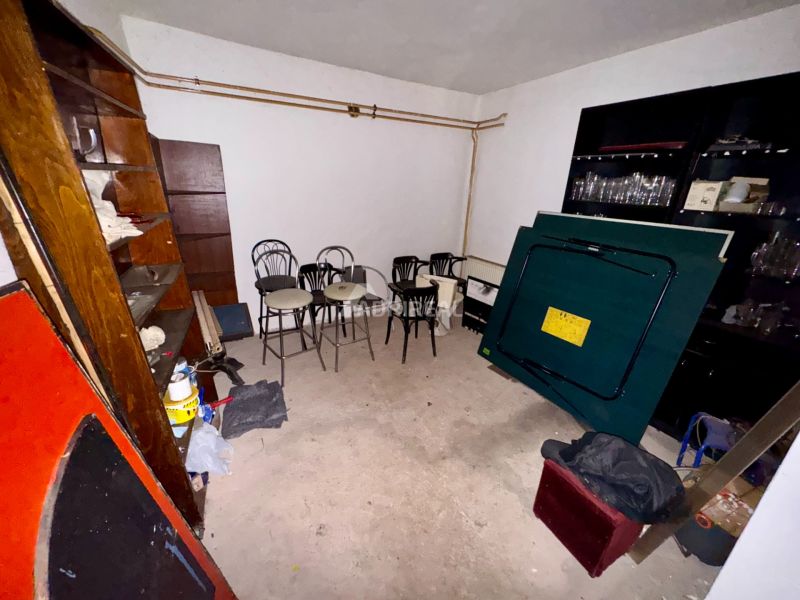 A basement in a family house with accumulated furniture and various items on a concrete floor.