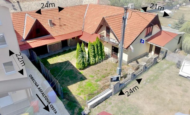 A family house in the village of Dobrá Niva with a red roof and a yard surrounded by a fence.