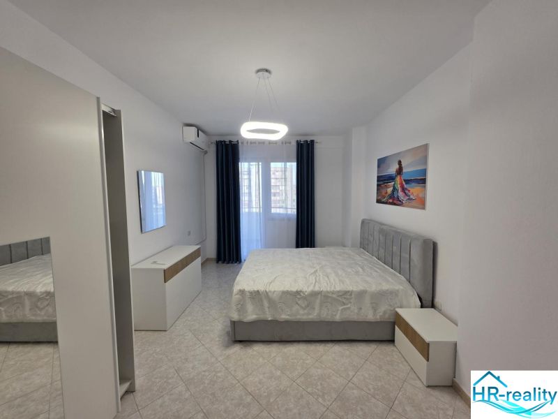 Bedroom in a 2-room apartment with a bed, white furniture, and a painting on the wall.