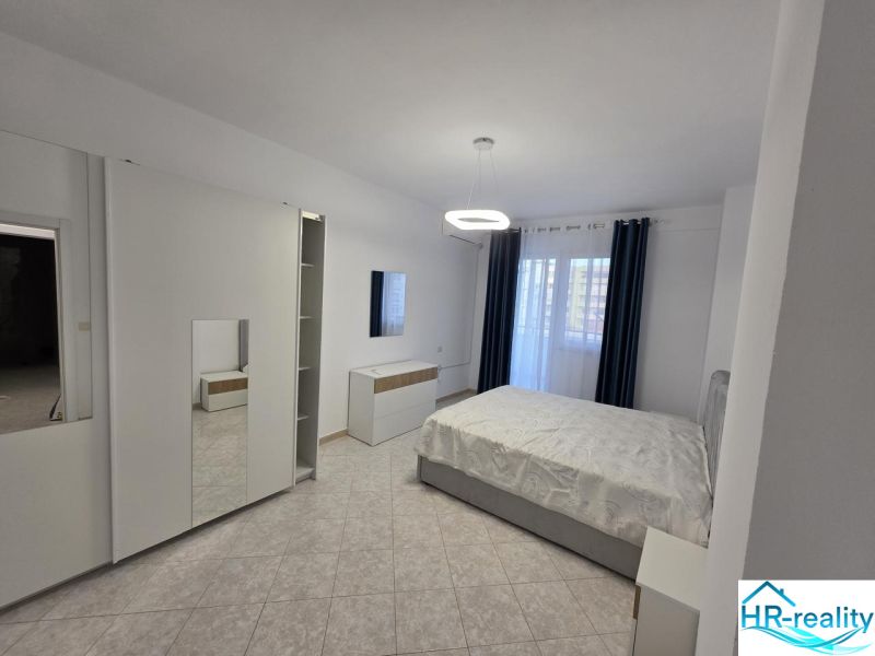 Bright bedroom with a bed, wardrobe, tiles, and curtains in a 2-room apartment.