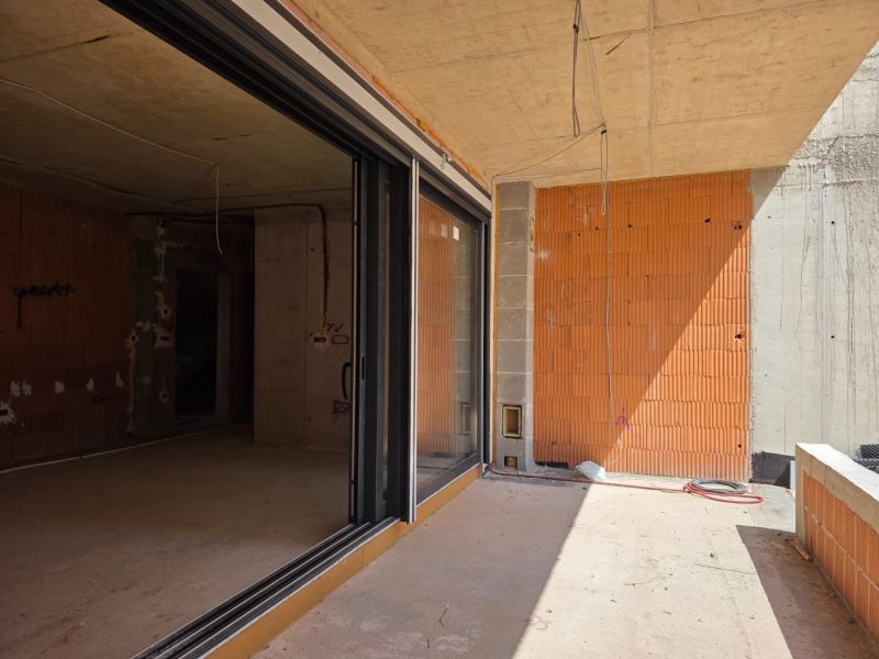 Unfinished 3-room apartment in SRIMA with glass sliding doors and bare brick walls.