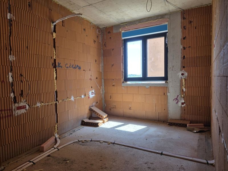 Unfinished room in a 3-room apartment with exposed brick walls and a window.