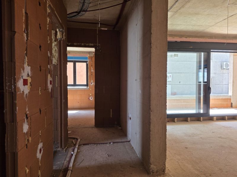 Unfinished interior of a 3-room apartment with large glass doors and masonry.
