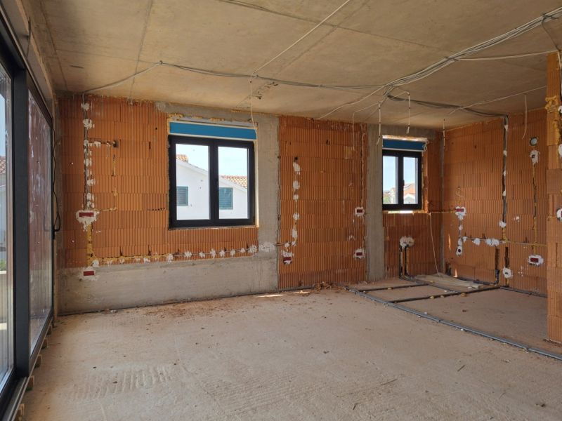The interior of a 3-room apartment under construction with bare brick walls and plastic windows.