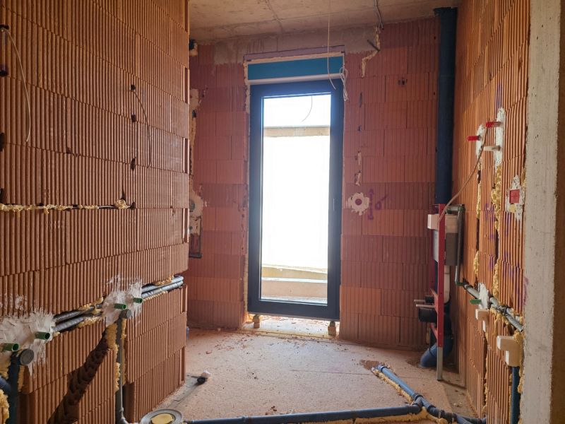 An unfinished room with raw brick walls and an exit to the balcony in a 3-room apartment.