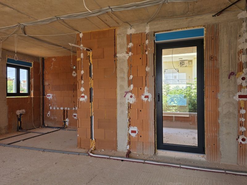Under-construction 3-room apartment with brick walls and electrical installation prepared for assembly.