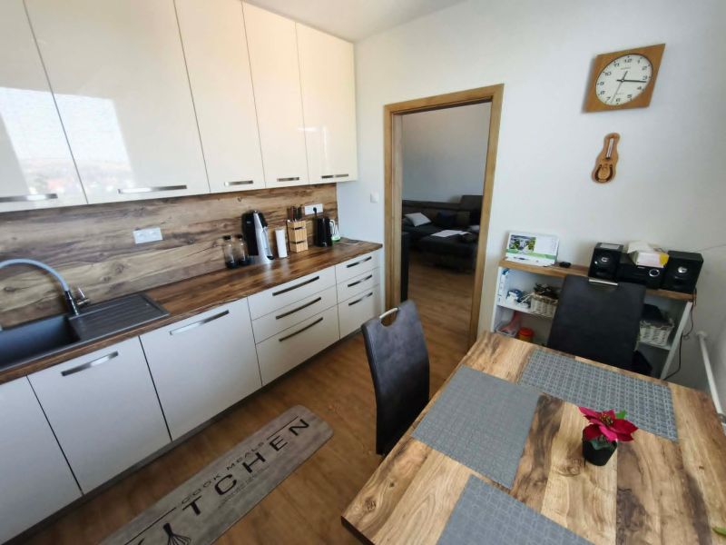 A kitchen with white cabinets and a wood-patterned floor in a 3-room apartment.