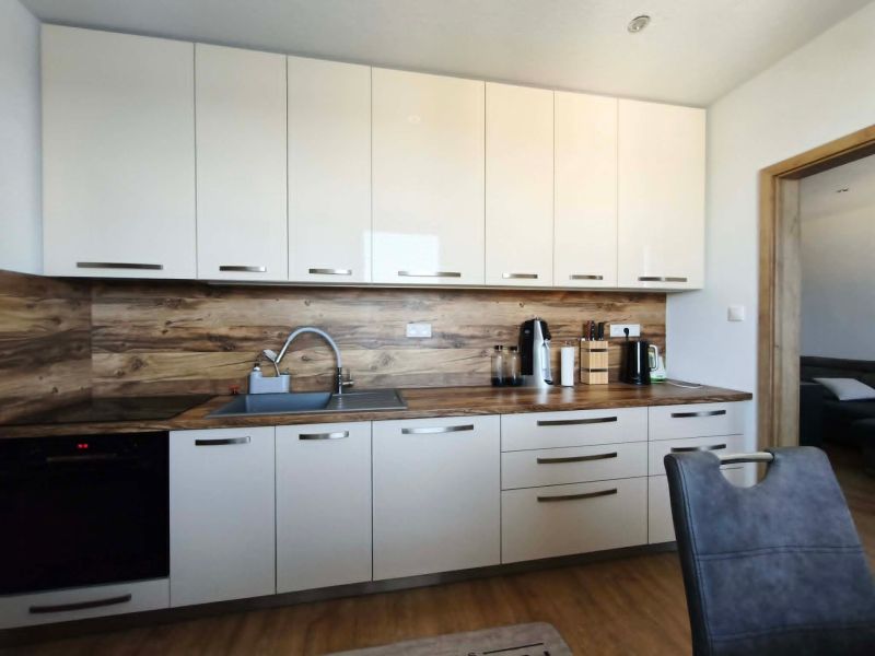 A kitchen in a 3-room apartment with white cabinets and a wood-patterned floor.