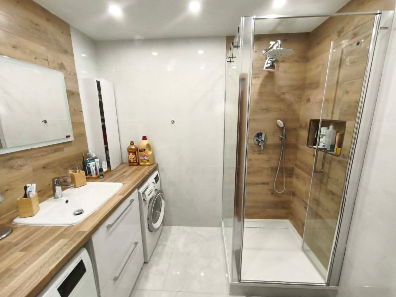 Bathroom with wood-patterned flooring in a 3-room apartment, modern furnishings, and a shower enclosure.