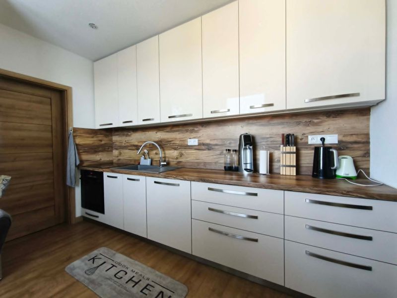 A kitchen in a 3-room apartment with white cabinets and a wood-patterned floor.