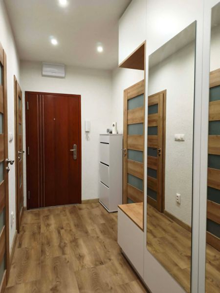 A hallway with a wooden decor floor and a mirrored wardrobe in a 3-room apartment.