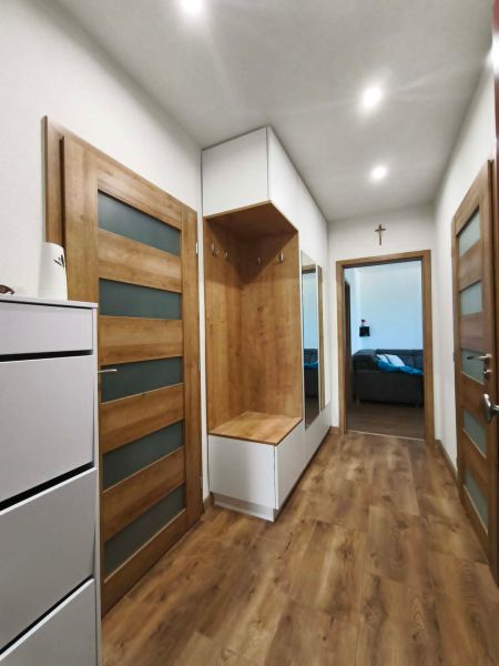 A hallway in a 3-room apartment with a wooden decor floor and wooden doors.