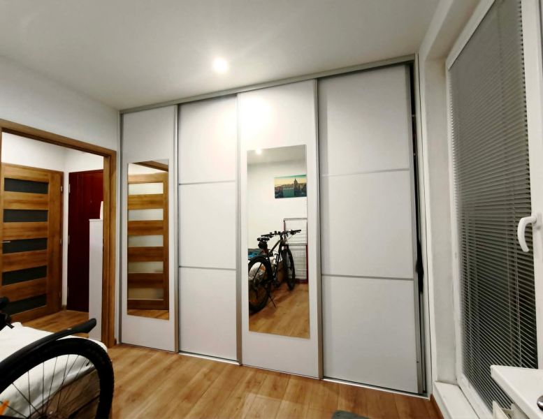Bedroom with a wardrobe and bicycles in a 3-room apartment; floor with wood decor.