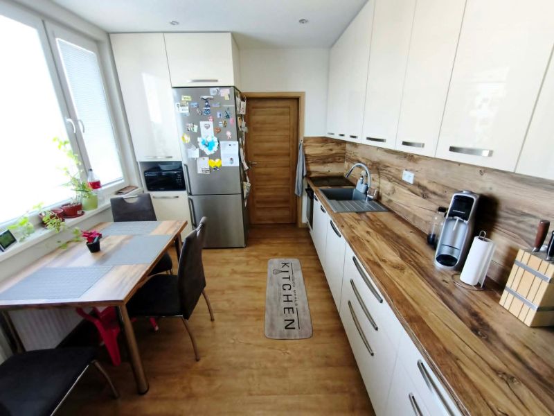 A kitchen in a 3-room apartment with a wood-decor floor, a table, and modern equipment.