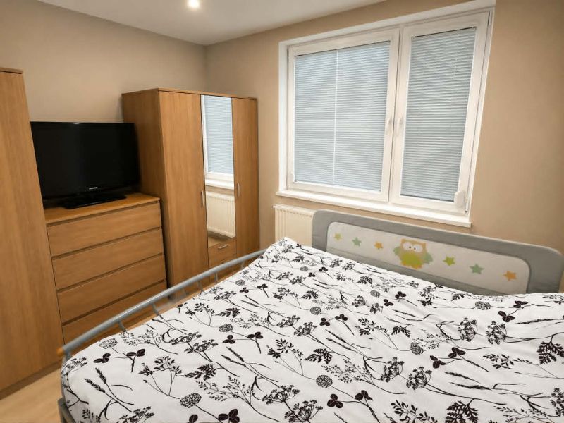 A bedroom in a three-room apartment with wooden decor furniture and a television.