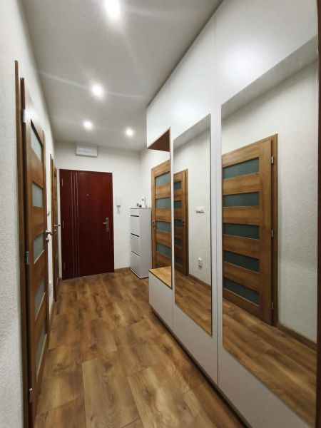 A hallway with mirrors, wooden doors, and a floor with a wooden decor in a 3-room apartment.