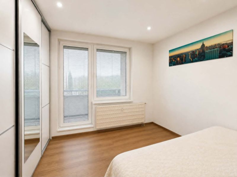 Bedroom in a 3-room apartment with a bed, built-in wardrobe, and floor with wood decor.