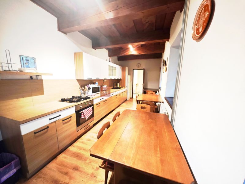 A kitchen in a cottage with a wooden decor floor, wooden ceiling, and dining table.